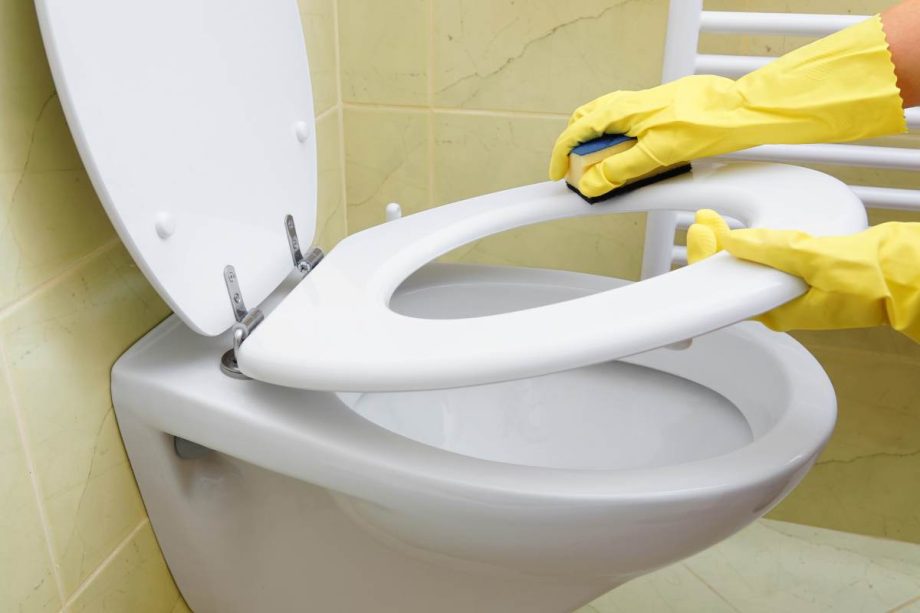 Een man maakt de wc-bril schoon.