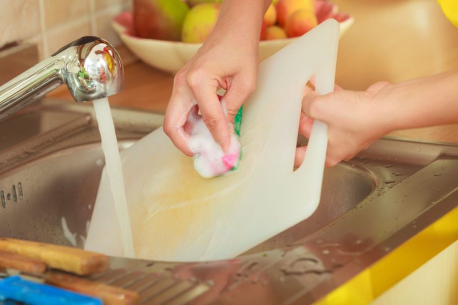 Het plastic snijplank onder de kraan afspoelen.