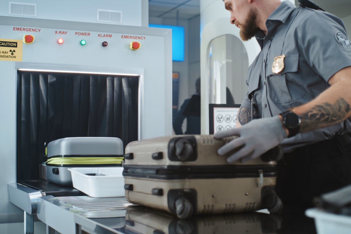 Een medewerker inspecteert handbagage op de luchthaven.
